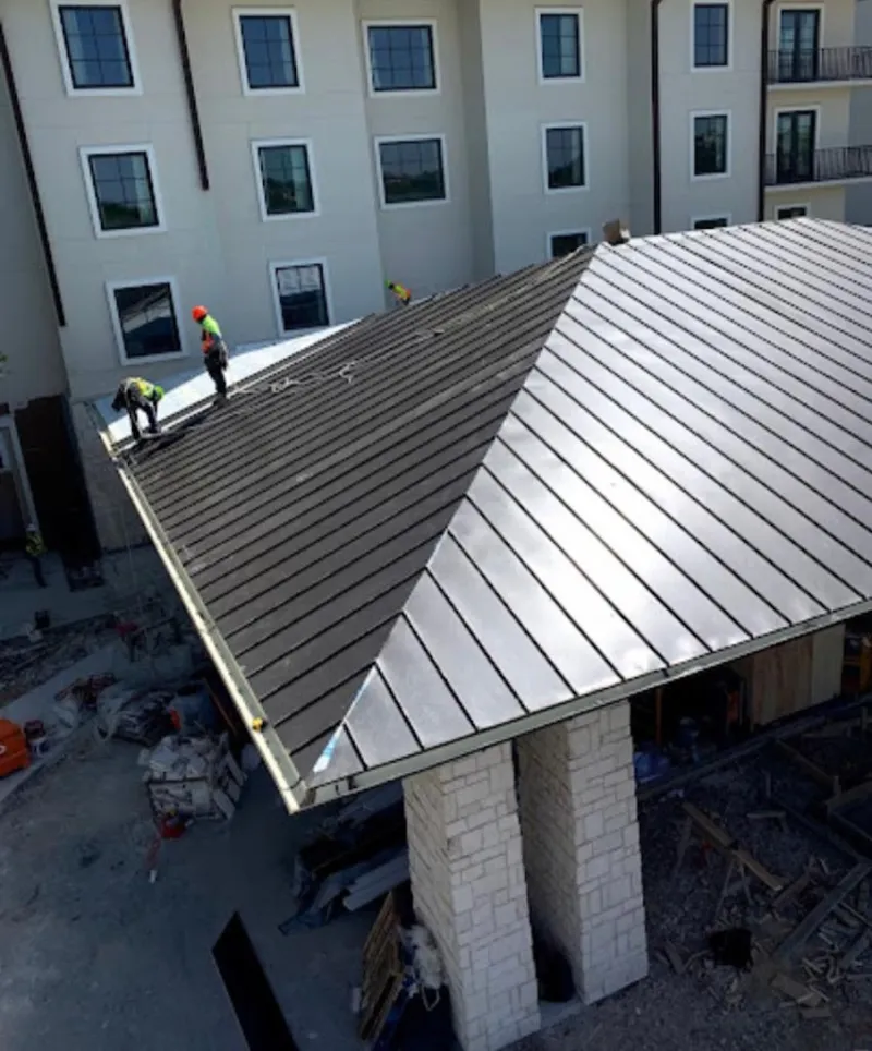 Crew installing standing seam metal roof panels on a commercial project in Bemidji